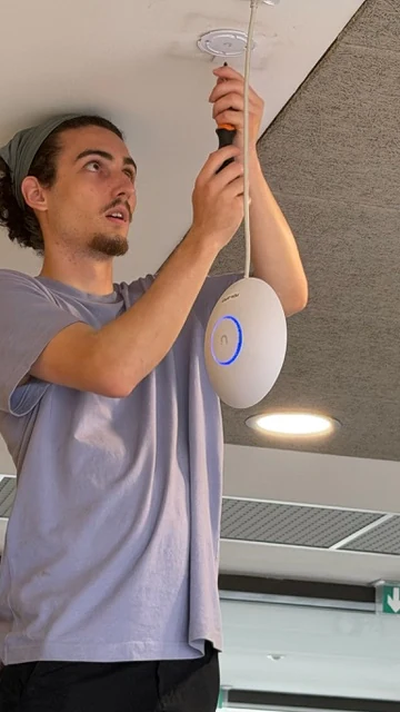 Scott fixe le support d'une borne Wi-Fi au plafond, avant le raccordement