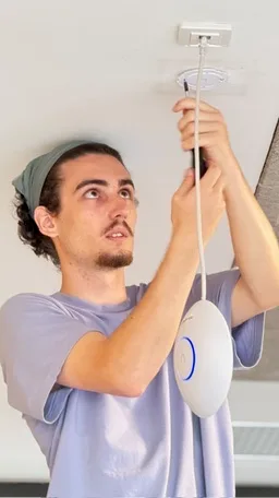 Un technicien WiFeel installe une borne Wi-Fi au plafond